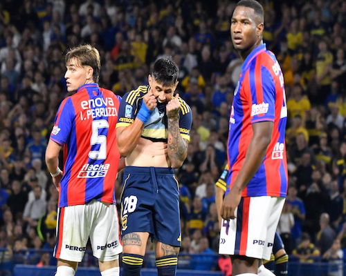 Adam Bareiro se lleva la camiseta a la boca mientras dos futbolistas de San Lorenzo lo observan durante el partido en La Bombonera.