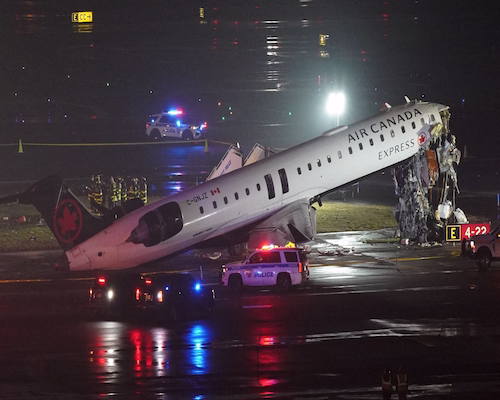 Restos de un avión de Air Canada Express tras una colisión en pista durante la noche, con presencia de equipos de emergencia y vehículos policiales