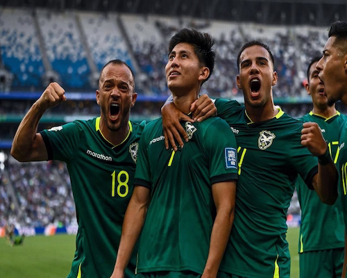 Jugadores de Bolivia celebran un gol abrazados y con gestos de euforia durante el partido en un estadio lleno