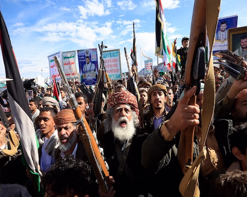 Manifestantes armados participan en una protesta masiva en Yemen, con banderas y carteles políticos, en medio de la escalada del conflicto en Medio Oriente