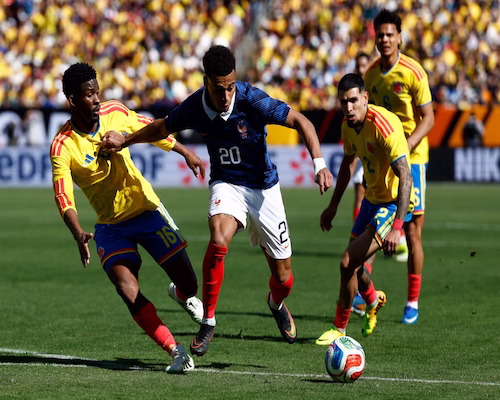 Désiré Doué disputa la posesión del balón ante la presión de dos jugadores de Colombia en un amistoso internacional