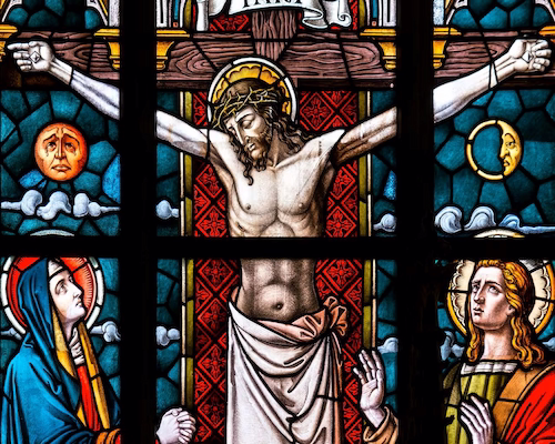 Vitral religioso que representa a Jesucristo crucificado en la cruz, acompañado por la Virgen María y el apóstol Juan observando la escena