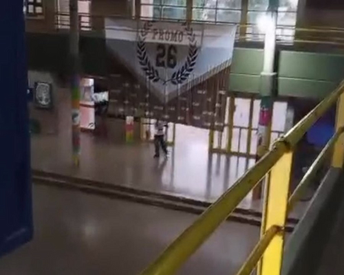 Interior de un colegio en San Cristóbal, con un estudiante caminando por el hall principal del establecimiento