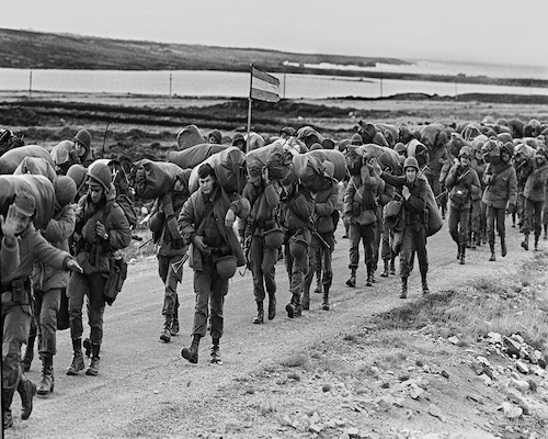 Soldados argentinos marchan en fila cargando equipos y mochilas durante el desembarco del 2 de abril de 1982 en las Islas Malvinas
