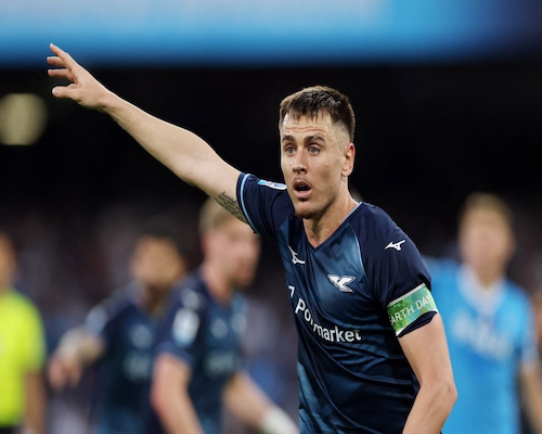 Primer plano del futbolista Patric, de la Lazio, con el brazo derecho extendido y señalando hacia arriba (expresión de dar una indicación) durante el partido contra el Napoli. Viste la camiseta azul oscuro suplente y el brazalete de capitán de “Earth Day”