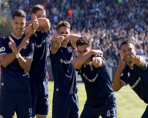 Jugadores de Independiente Rivadavia celebran un gol con un gesto grupal cubriéndose el rostro y simulando pistolas con las manos