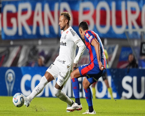 Neymar Jr. con la indumentaria del Santos FC ejecutando un pase frente a la marca de un jugador de San Lorenzo durante un partido de la Copa Sudamericana