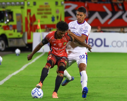 Jugador de Deportivo Cuenca disputa el balón con un futbolista de San Lorenzo en un partido de la Copa Sudamericana