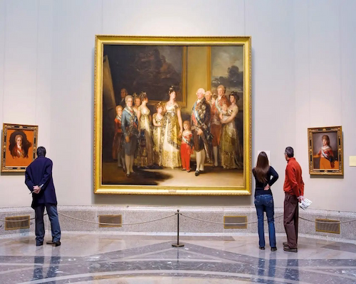 Visitantes observando la pintura “La familia de Carlos IV” de Francisco de Goya en el Museo del Prado.