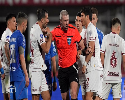 Jugadores de Lanús le reclaman al árbitro por el cobro de un penal para la U. de Chile en tiempo de descuento.