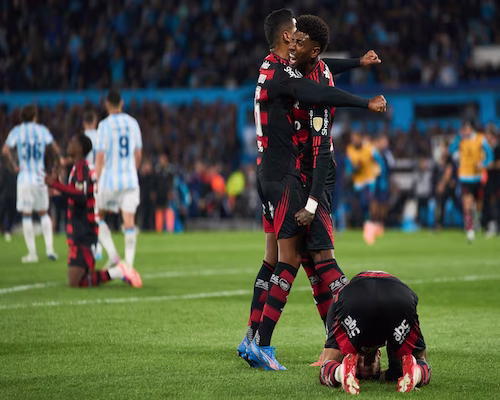 Jugadores de Flamengo celebran arrodillados y abrazados tras eliminar a Racing de la Copa Libertadores.