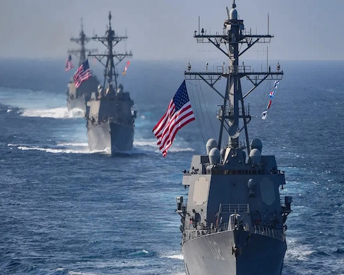 Buques de guerra de la Armada de Estados Unidos navegan en formación en aguas de Medio Oriente con banderas estadounidenses izadas.
