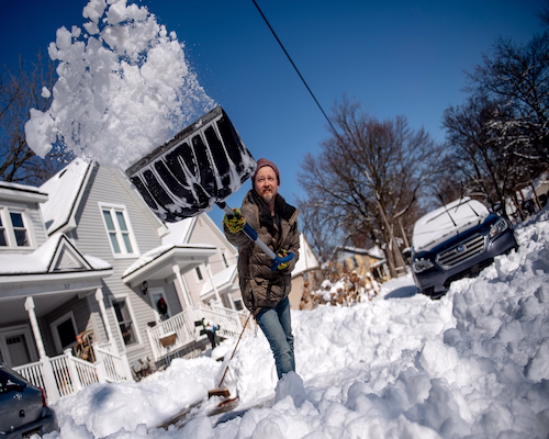 Hombre retirando la nieve acumulada de la acera con una pala durante una intensa tormenta invernal en Estados Unidos