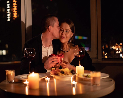 Pareja brindando durante una cena romántica con velas por el Día de San Valentín.