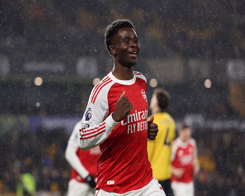 Bukayo Saka celebra un gol con la camiseta de Arsenal bajo la lluvia en el Molineux Stadium