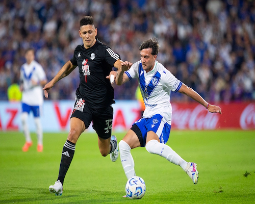 Jugador de Vélez Sarsfield disputa el balón ante un futbolista de Deportivo Riestra durante el empate sin goles en Liniers