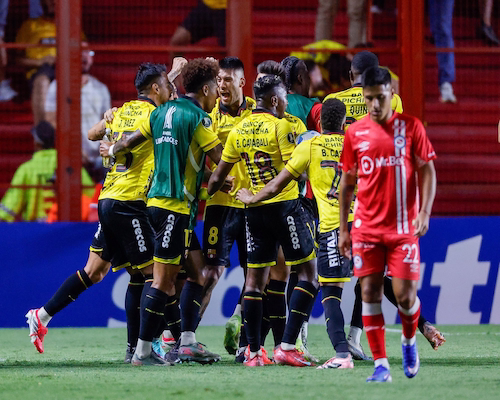 Jugadores de Barcelona SC celebran el gol ante Argentinos Juniors mientras un futbolista local se retira con gesto de decepción.