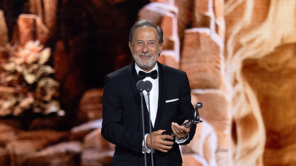 El actor Guillermo Francella sonriendo frente al micrófono mientras sostiene una estatuilla de los Premios Platino.