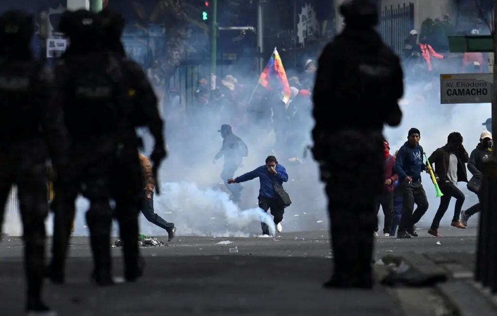 Manifestantes corren entre gases lacrimógenos durante enfrentamientos con la Policía en una protesta en La Paz, Bolivia