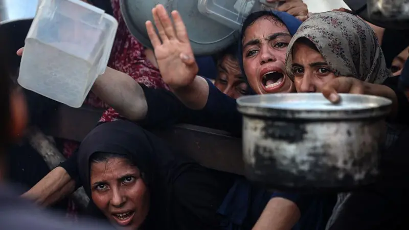 Mujeres en Gaza intentan recibir comida en un centro de distribución