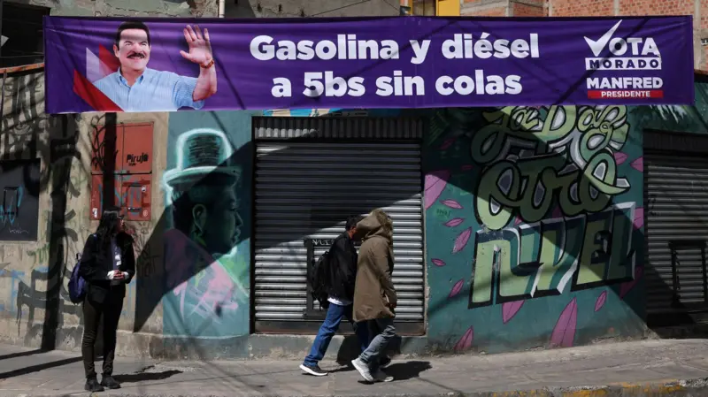 La gente pasa junto a una pancarta del candidato presidencial boliviano Manfred Reyes Villa, del partido "Súmate", en La Paz
