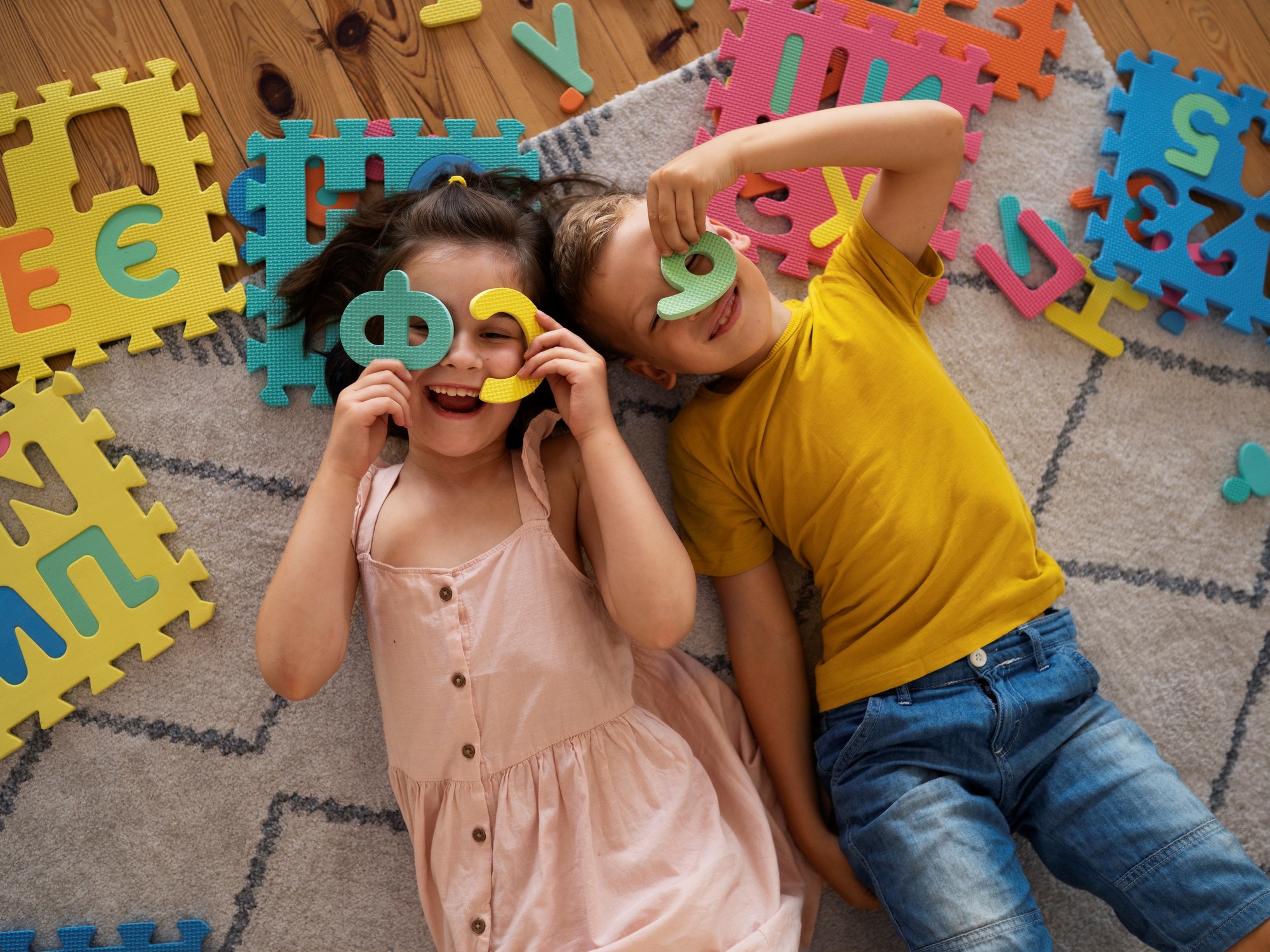 Niños recostados en el suelo, jugando con números y letras de goma eva