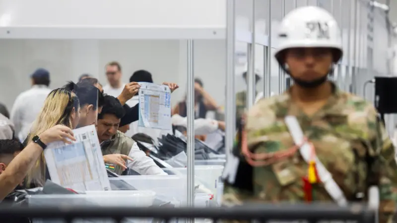 Se ve a un hombre de seguridad en primer plano y al fondo se ven trabajadores del Tribunal Electoral haciendo el recuento de votos