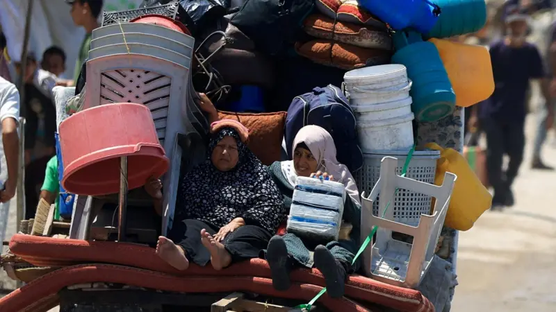 Mujer palestinas huyen de Gaza en un carro lleno de sus pertenencias