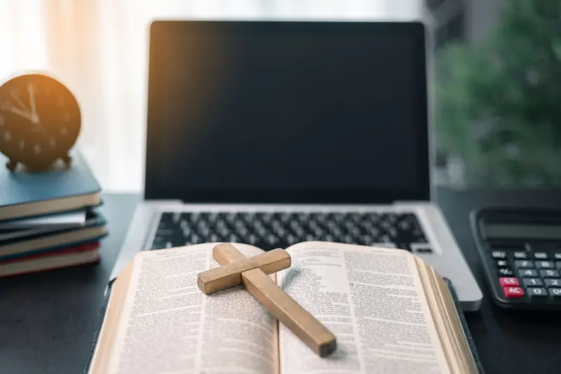 Una computadora junto a una Biblia y un crucifijo