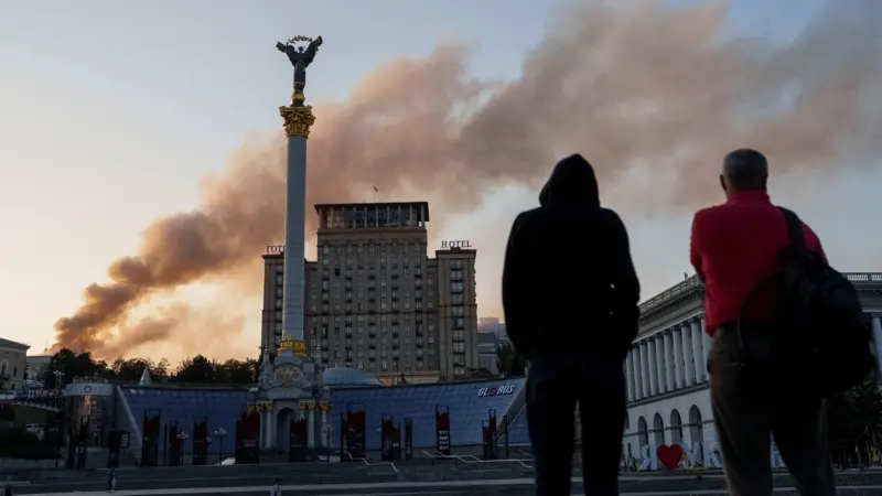 Unos hombres ven la columna de humo que sale del edificio del Gabinete