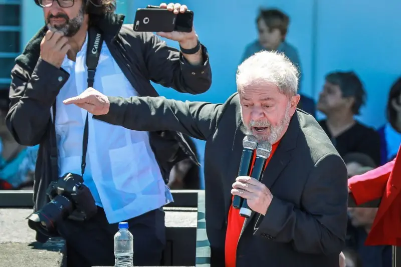 Lula da Silva pronuncia un discurso desde una tarima mientras carga dos micrófonos en la mano izquierda