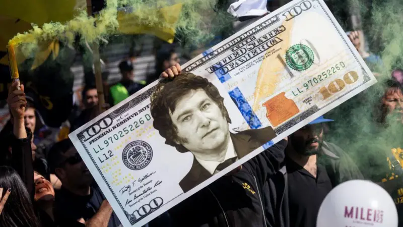 Un simpatizante de Javier Milei sostiene un billete gigante de un dólar estadounidense con la cara de Javier Milei