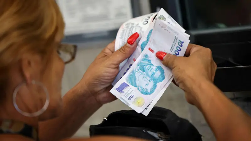 Una mujer contando billetes de pesos argentinos