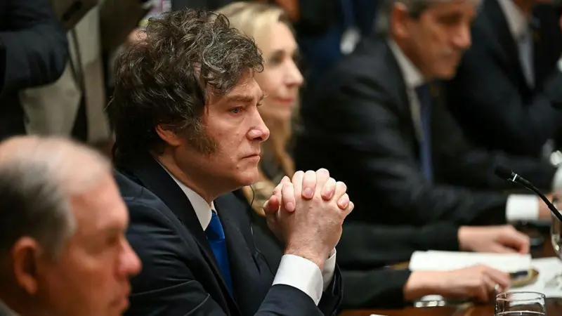 Milei sentado en la mesa de la Casa Blanca con las manos entrelazadas.