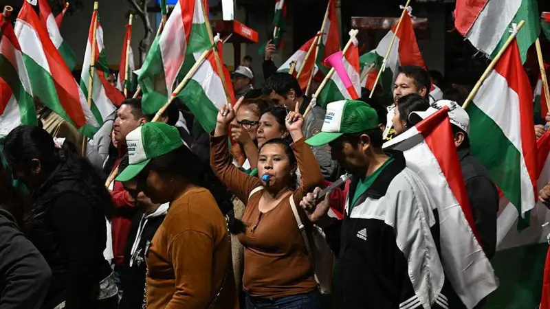 Bolivianos con banderas alusivas al PDC celebrando durante la noche.