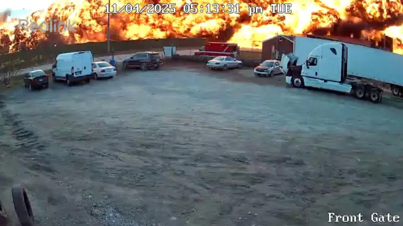 Imagen de cámara de de seguridad que muestra un estacionamiento con la estela en llamas del accidente aéreo en Kentucky