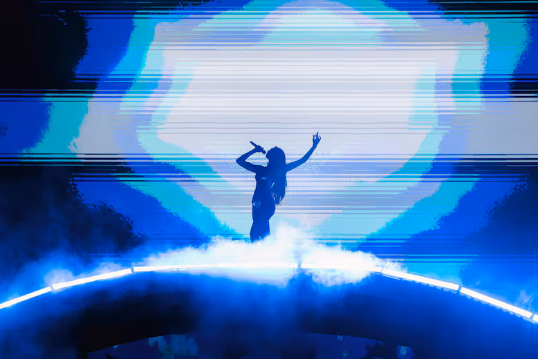 Se observa la silueta de Dua Lipa con un micrófono en mano y levantando la otra mano durante el concierto.