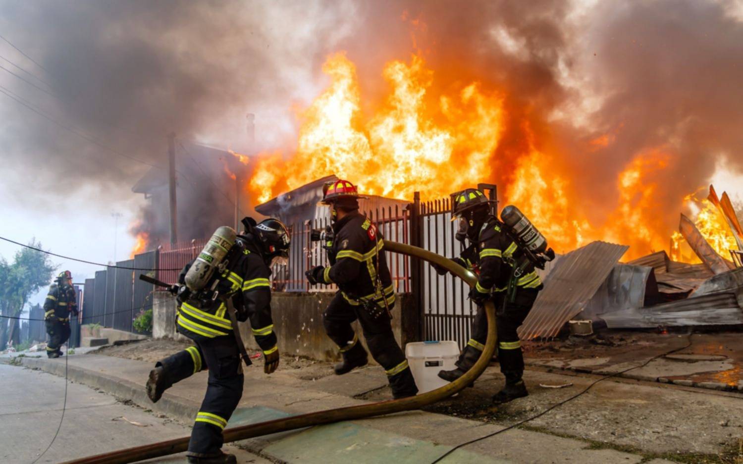Bomberos combaten un incendio en una casa mientras los incendios forestales arden en Lirquen, Chile