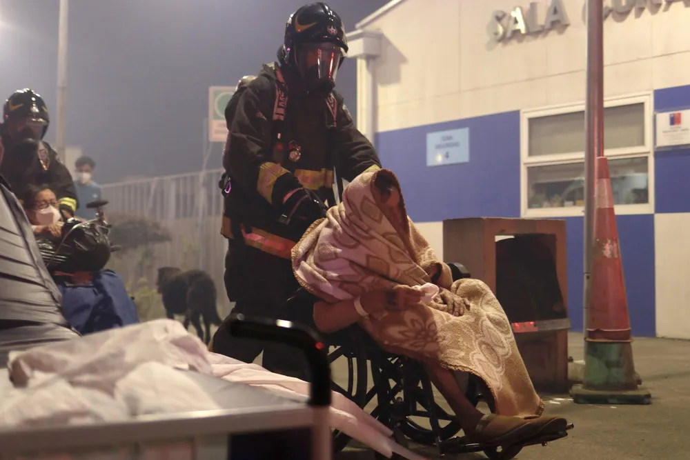 Personal de emergencia asiste a una persona evacuada por los incendios forestales en el sur de Chile