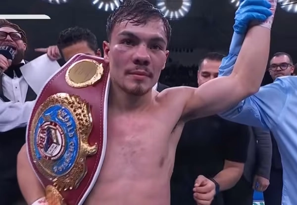Christian Medina celebra la victoria con el cinturón mundial gallo WBO mientras el árbitro le levanta la mano.